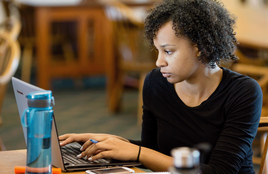 A woman works on her computer in the library