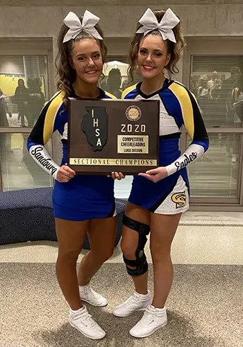 Kate and Meghan McCurdy hold a 2020 IHSI Cheerleading trophy