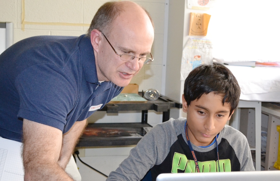 Adam Poetzel assists student with coding