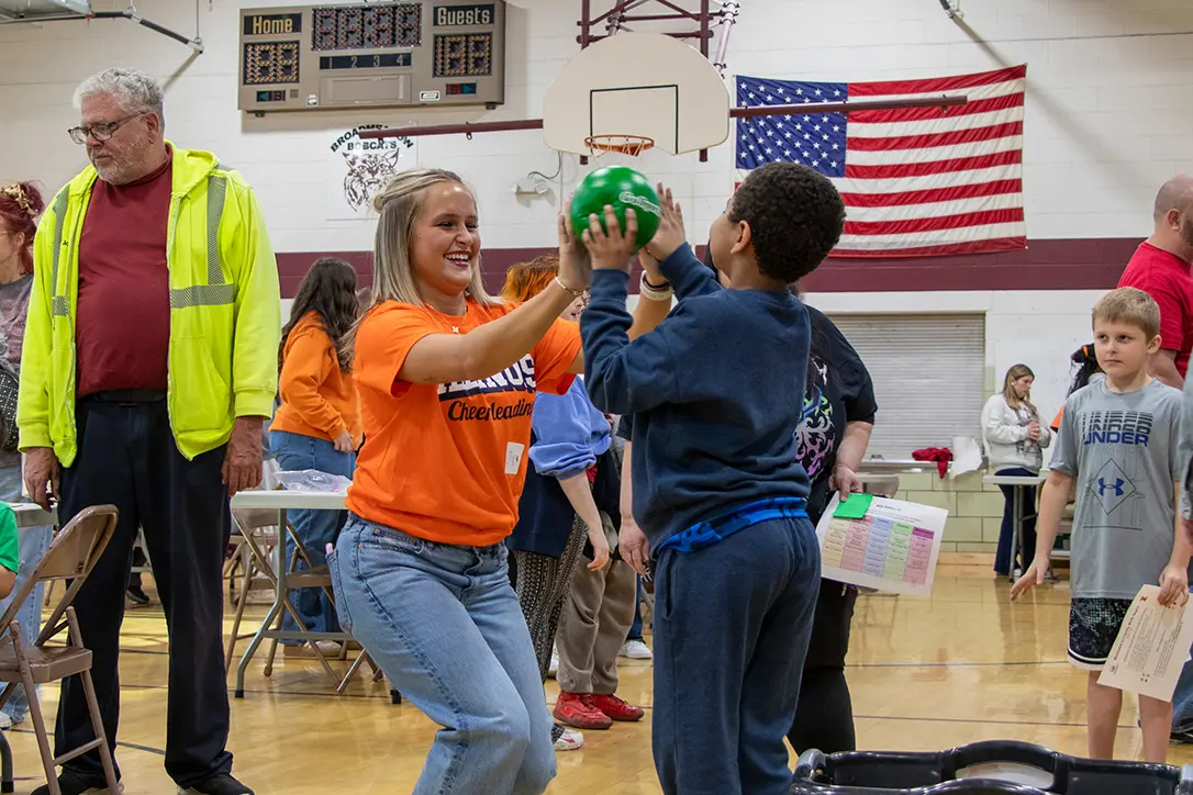 student teacher high fives a student playing a ball game at the family math night event.