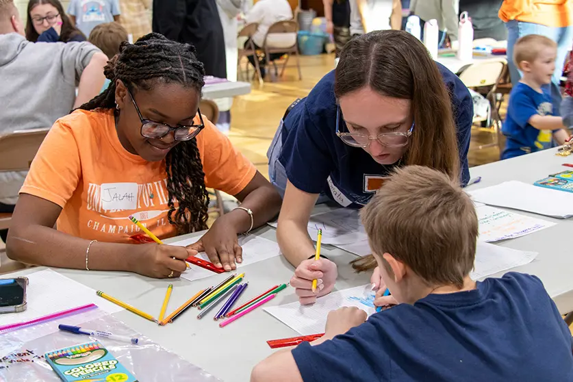 two student teachers work with a student at family math night